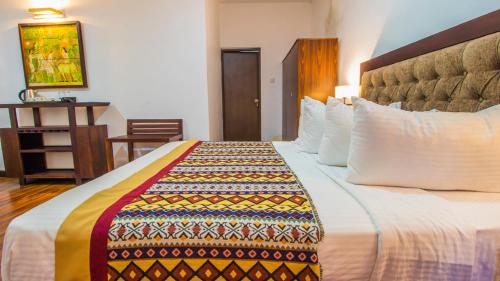 a hotel room with a bed with a colorful blanket on it at Pearl Royal Hotel, Colombo in Colombo