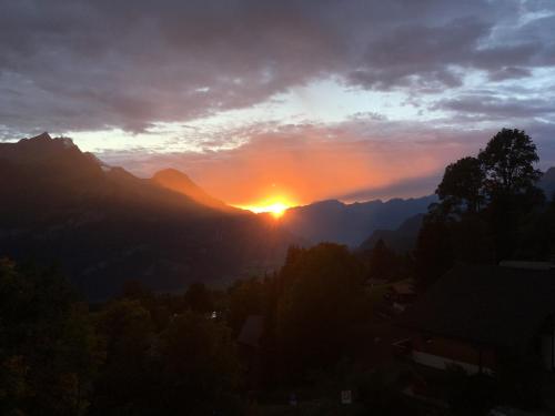 a sunset in the mountains with the sun setting at Chalet Orchis in Hasliberg Wasserwendi