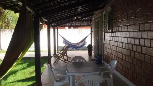 a porch with a table and chairs and a hammock at Casa de Arlete in Barra do Gil