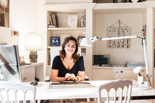 a woman sitting at a desk in a kitchen at Giardino della Pieve Relais- Adult Only in Cascina