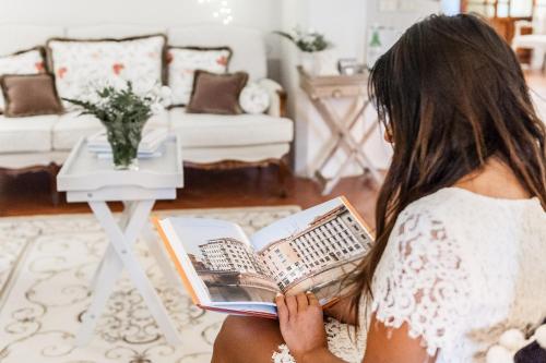 a woman sitting on a couch reading a book at Giardino della Pieve Relais- Adult Only in Cascina