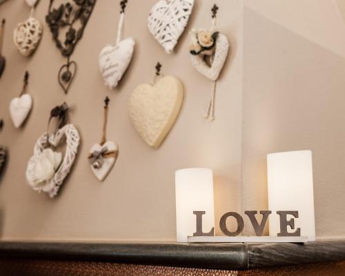 a bunch of hearts hanging on a wall with candles at Giardino della Pieve Relais- Adult Only in Cascina