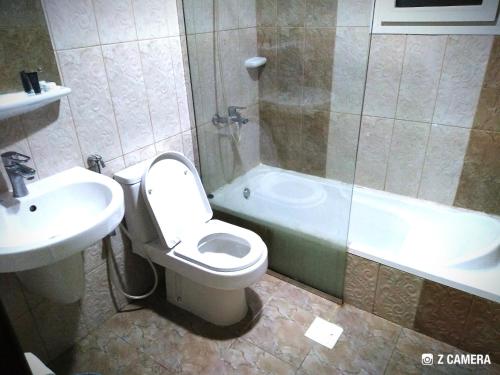a bathroom with a toilet and a tub and a sink at Al Mabila Hotel in Seeb