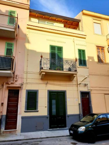 un bâtiment avec des portes vertes et une voiture garée devant dans l'établissement Rifinito bilocale in centro, Casa Verdi, 2° Piano, à Bagheria