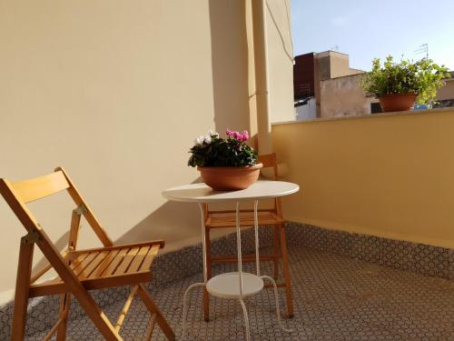 une table avec une plante à côté de deux chaises dans l'établissement Rifinito bilocale in centro, Casa Verdi, 2° Piano, à Bagheria