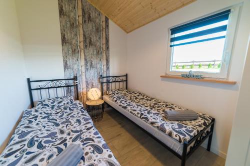 two beds in a room with a window at Strumyk Marzeń in Mikołajki