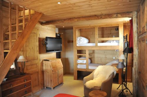 a bedroom with two bunk beds and a television at Hôtel Chalet Alpage in La Clusaz