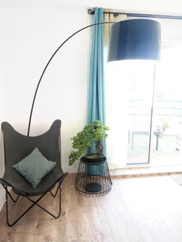 a floor lamp in a room with a chair and a plant at Les Clés du Bonheur by Beds4Wanderlust, 47m2 avec Terrasse privative & Parking-RER B TGV 10min-Orly 20min in Massy