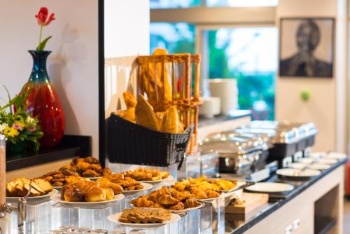 a buffet line with plates of food and pastries at ONOMO Hotel Conakry in Conakry