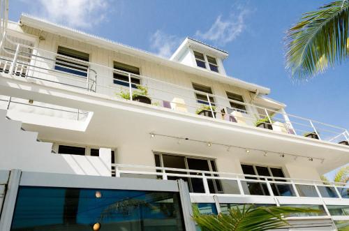 a white building with a balcony and a palm tree at Numero Uno Beach House in San Juan