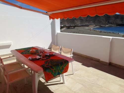 a table and chairs in a room with a view of a beach at ÁTICO EN PRIMERA LINEA DE PLAYA in Gran Tarajal