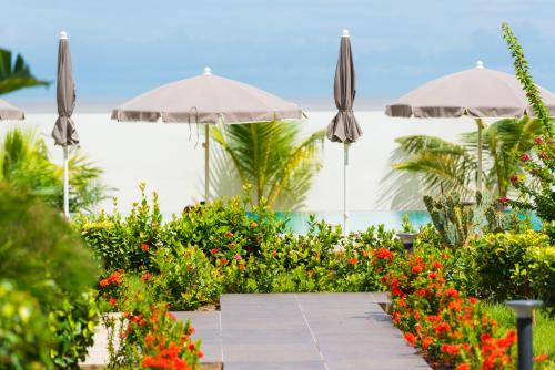 a garden with umbrellas and flowers on a patio at ONOMO Hotel Conakry in Conakry