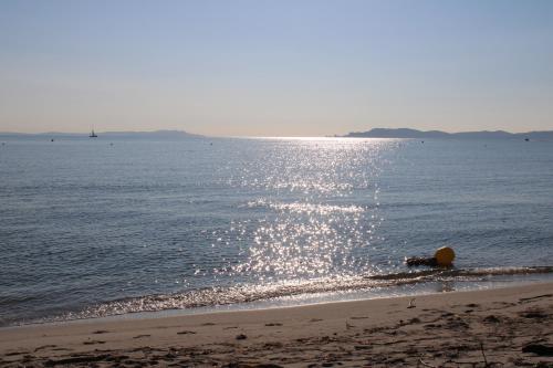 a beach with the sun reflecting on the water at 5 avenue de la Gavine Résidence Hyères Parc in Hyères