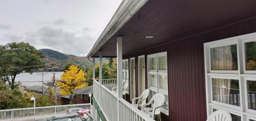 a house with white chairs on a porch with a view at Pinebrook Motel in Lake George