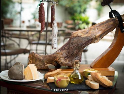 ein Tisch mit einem Stück Fleisch, Käse und Brot in der Unterkunft Hotel El Faixero Tradicional in Cinctorres
