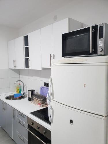a white kitchen with a microwave on top of a refrigerator at Guest House deluxe in Orašje