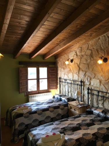ALTO DE LA RESERVA في Castronuño: غرفة نوم بسريرين وجدار حجري