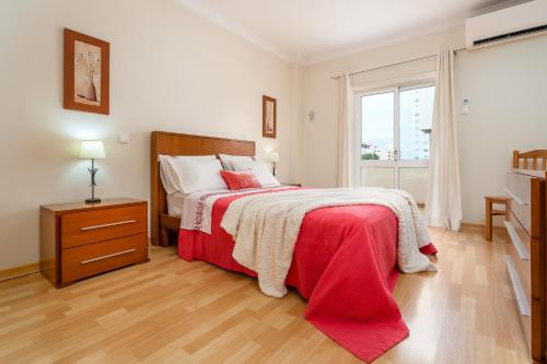 1 dormitorio con 1 cama con manta roja y ventana en Cozy Apartment PORTIMÃO City Center, en Portimão
