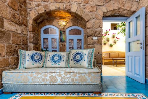 a couch in a room with a stone wall at Arabesque Arts & Residency in ‘Akko