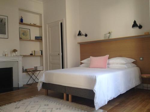 una camera da letto con un grande letto bianco con un cuscino rosa di La Traversière-Chambre d'hôtes a Tours