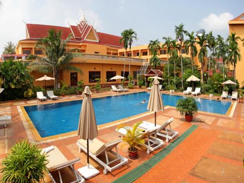 a pool at a resort with chairs and umbrellas at Angkor Hotel in Siem Reap