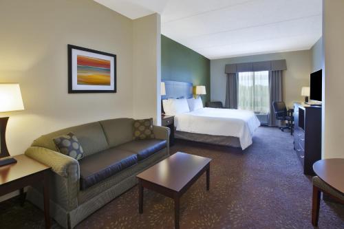 a hotel room with a bed and a couch at Holiday Inn Express & Suites Geneva Finger Lakes by IHG in Geneva
