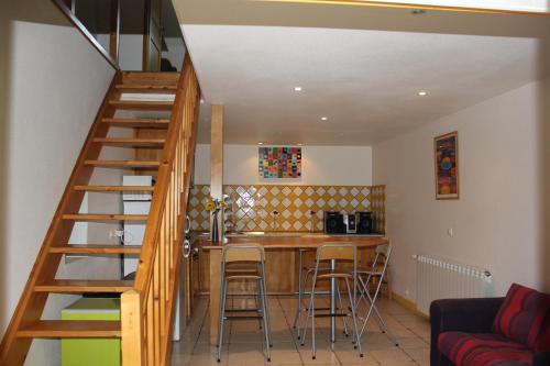 une cuisine avec un escalier et un bar avec des tabourets dans l'établissement Au coeur des Volcans d'Auvergne, à Ceyssat