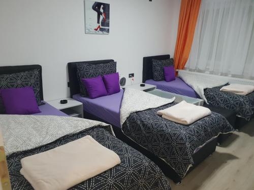 a room with three beds and purple pillows at Guest House deluxe in Orašje