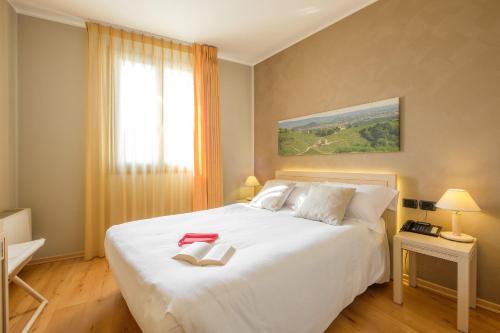 a bedroom with a white bed with two books on it at Wine Hotel San Giacomo Activity & Wellness in Paderno del Grappa