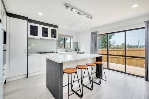 a kitchen with white cabinets and a counter with stools at Harmony Haven is close to airport in Auckland