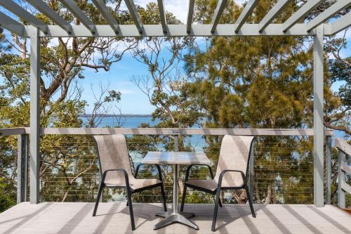 a table and chairs on a deck with a view of the ocean at The Edgewater on Greville in Sanctuary Point