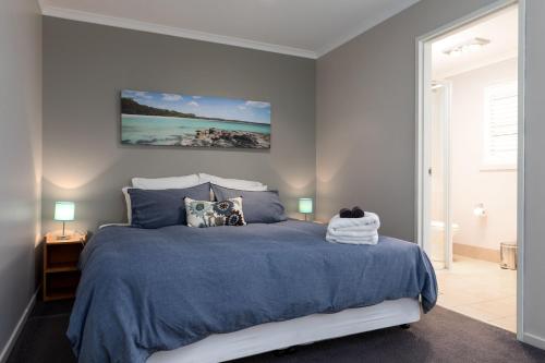 a bedroom with a bed with a blue comforter at The Edgewater on Greville in Sanctuary Point