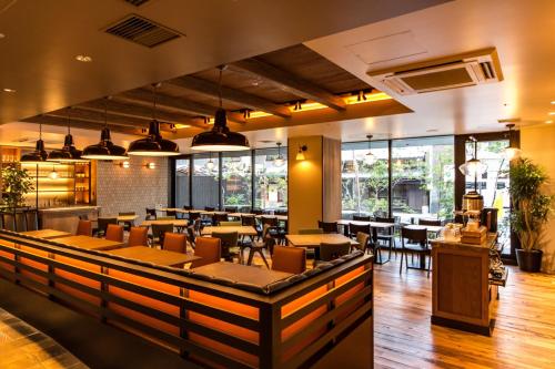 uma sala de jantar com mesas, cadeiras e janelas em Hotel Resol Trinity Kyoto em Quioto