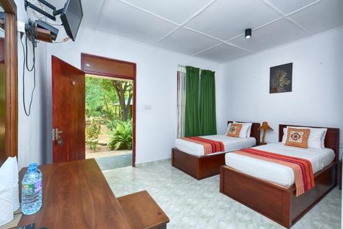 a hotel room with two beds and a table at Jays Holiday Resort in Habarana