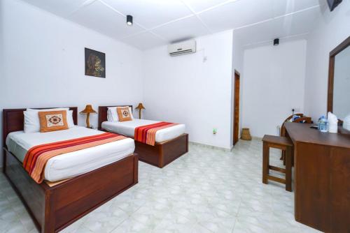 Habitación de hotel con 2 camas y escritorio en Jays Holiday Resort, en Habarana