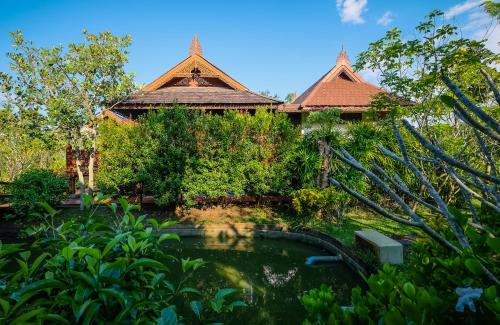 a garden with a pond and a building with a house at Rommai Villa Chiang Rai in Ban Pa Sang (1)