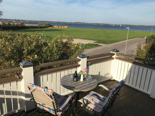 a table and chairs on a deck with a view of the ocean at Villa Wiegand - a room with a view in Holbæk