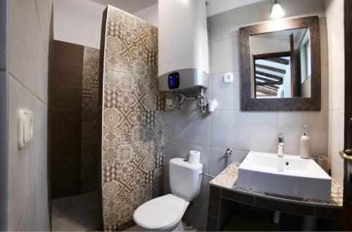 a bathroom with a sink and a toilet and a mirror at Tulipán Apartman in Eger