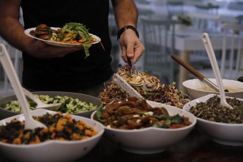 a person holding a plate of food with bowls of food at Bait Alfa Kibbutz Country Lodging in Bet Alfa