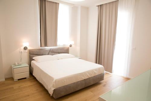 a white bedroom with a bed and a window at Boutique Hotel Enia in Prato