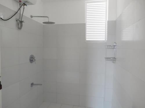 a white bathroom with a shower and a tub at Mountain Wave Hotel and Surfshop in Hikkaduwa