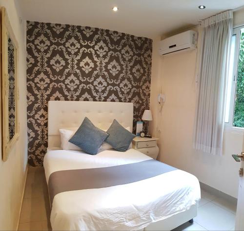 a bedroom with a large white bed with blue pillows at Central Hotel in Tel Aviv