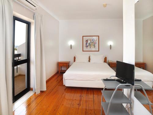 a bedroom with a bed and a desk with a computer at Portimão Center Hotel in Portimão