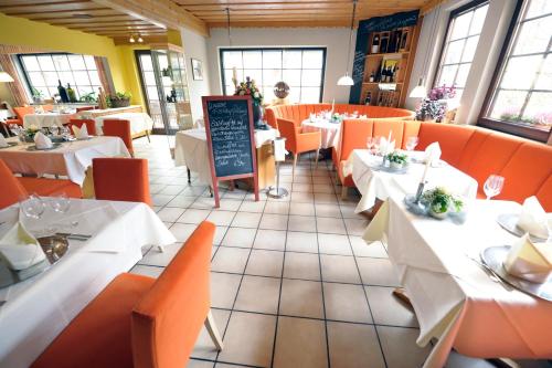 ein Restaurant mit Tischen und orangefarbenen Stühlen und einem Schild in der Unterkunft Waldhotel Felschbachhof in Ulmet