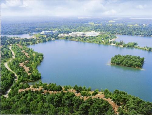 an aerial view of a large lake with trees at Hotel De Vossemeren by Center Parcs in Lommel
