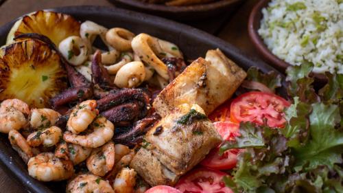 a plate of food with shrimp and a salad at Sombra e Água Fresca Floresta in Pipa