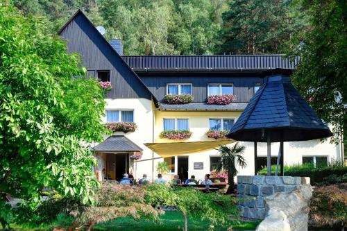 Un bâtiment avec des personnes assises sous un parasol devant lui dans l'établissement Pension Am Nationalpark, à Stadt Wehlen