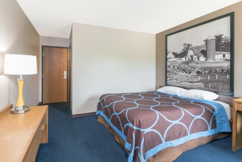 a hotel room with a bed and a painting on the wall at Super 8 by Wyndham Milbank SD in Milbank