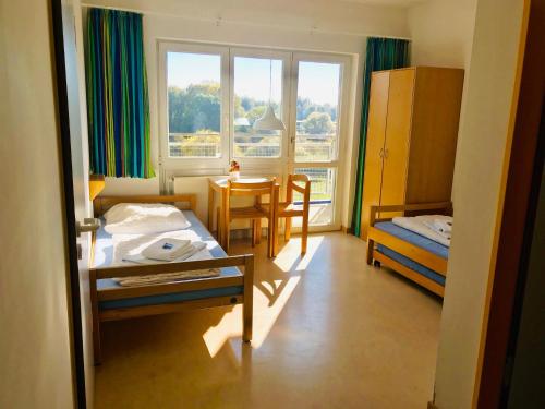 Schlafzimmer mit einem Bett, einem Tisch und einem Fenster in der Unterkunft Jugendherberge Hannover in Hannover
