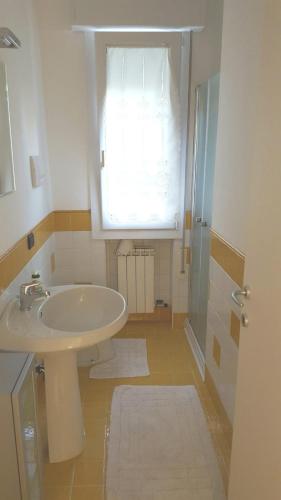 a white bathroom with a sink and a window at Casa La Rosa in Montegrotto Terme
